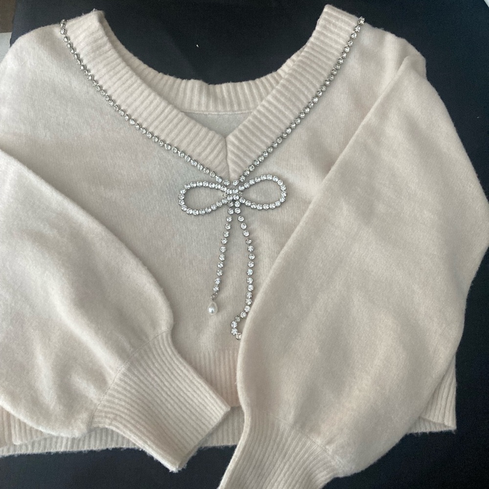 Women’s size XS express sweater with rhinestone and bow detail.